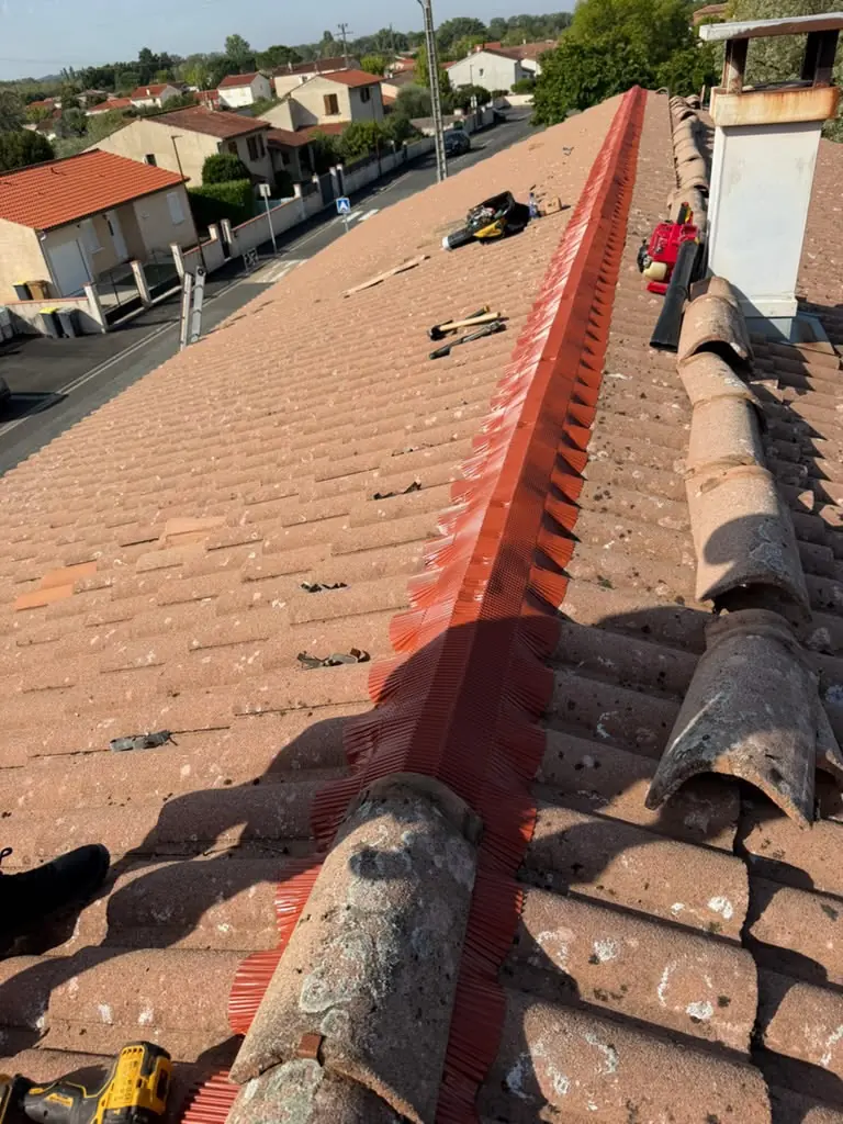 Pose d'un closoir de faîtage en cours sur une toiture en tuiles