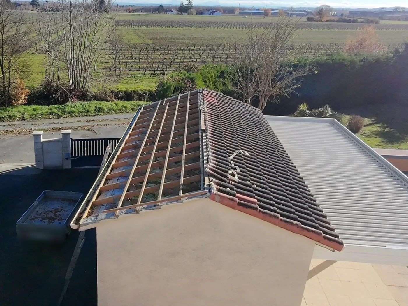 Toit de garage en cours de reprise : anciennes tuiles d'un côté, liteaux apparents de l'autre